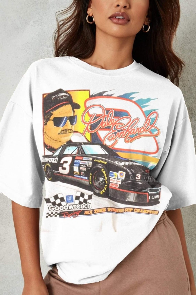 May include: White t-shirt with a vintage-style graphic of a race car driver, a car, and the text "Dale Earnhardt" and "Goodwrench Racing".