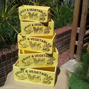 May include: Five yellow wooden crates stacked on top of each other. Each crate has the words "FRUIT & VEGETABLES" printed on the front in black lettering. The crates are decorated with a black and white illustration of fruit and vegetables.