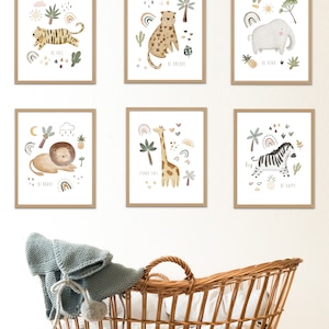 May include: Six framed prints with illustrations of jungle animals and motivational phrases. The prints are arranged in a grid pattern on a white wall. The prints feature a tiger, leopard, elephant, lion, giraffe, and zebra. The phrases on the prints are "Be Free", "Be Unique", "Be Kind", "Be Brave", "Stand Tall", and "Be Happy".