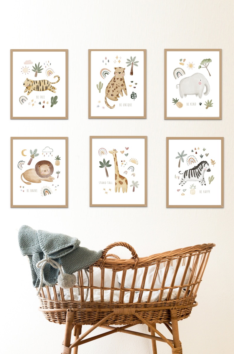 May include: Six framed prints with illustrations of jungle animals and motivational phrases. The prints are arranged in a grid pattern on a white wall. The prints feature a tiger, leopard, elephant, lion, giraffe, and zebra. The phrases on the prints are "Be Free", "Be Unique", "Be Kind", "Be Brave", "Stand Tall", and "Be Happy".