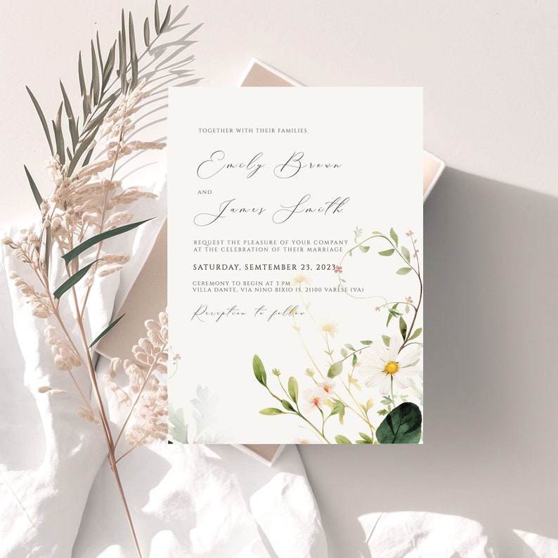 May include: Wedding invitation with a floral design featuring white flowers and green leaves. The invitation is for Emily Brown and James Smith, and the wedding is scheduled for Saturday, September 23, 2023.