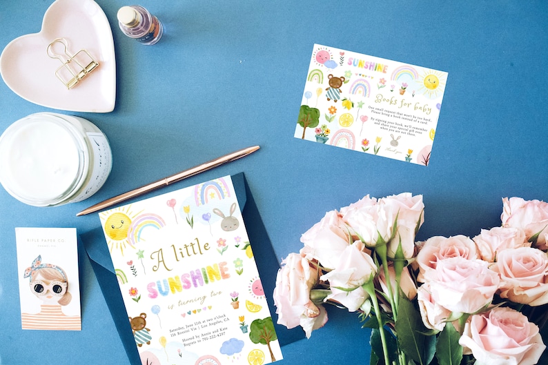 May include: A colorful baby shower invitation with a rainbow, sun, bunny, and teddy bear. The invitation reads "A little sunshine is turning two".