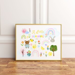 May include: A gold framed print with a white background and colorful illustrations of a bear, a bunny, rainbows, lemons, flowers, and a sun. The text "A Little Sunshine" is in the center of the print.