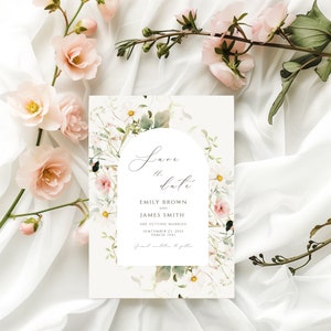 May include: Save the date card with a watercolor floral design featuring white and pink flowers. The text reads "Save the date" with the names Emily Brown and James Smith, the date September 23, 2021, and the location Varese (VA).