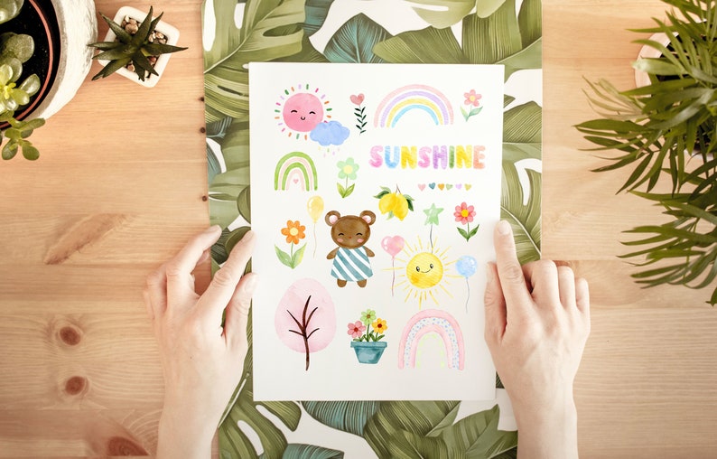 May include: A white card with watercolor illustrations of a bear, flowers, rainbows, suns, and lemons. The text "SUNSHINE" is written in rainbow colors.