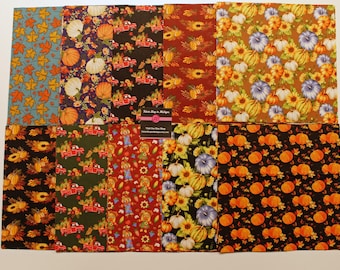 Puede incluir: Un conjunto de 10 cuadrados de tela con varios patrones de temática otoñal. Los patrones incluyen calabazas, girasoles, hojas y camiones. Las telas son en tonos de naranja, marrón, verde, azul y rojo.