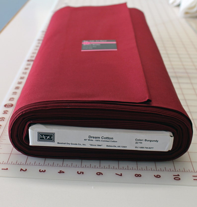 May include: A roll of burgundy red Dream Cotton fabric, 45 inches wide and 100% combed cotton. The fabric is made by Marshall Dry Goods Co., Inc. and is available in 25 yard increments.