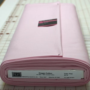 May include: A rolled bolt of pink Dream Cotton fabric, 45 inches wide, made of 100% combed cotton. The label indicates the color is pink and the bolt contains 25 yards of fabric. The fabric is from Marshall Dry Goods Co., Inc.
