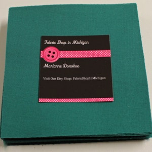 May include: A stack of teal fabric squares with a business card that reads "Fabric Shop in Michigan" with a pink polka dot border and the name "Marianne Donahue" and the text "Visit Our Etsy Shop: FabricsShopInMichigan".
