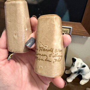 May include: Two small, brown ceramic salt and pepper shakers with gold lettering. The shaker on the right says "The Hard Way", "Sometimes I'll lay", "Mine down in it!"
