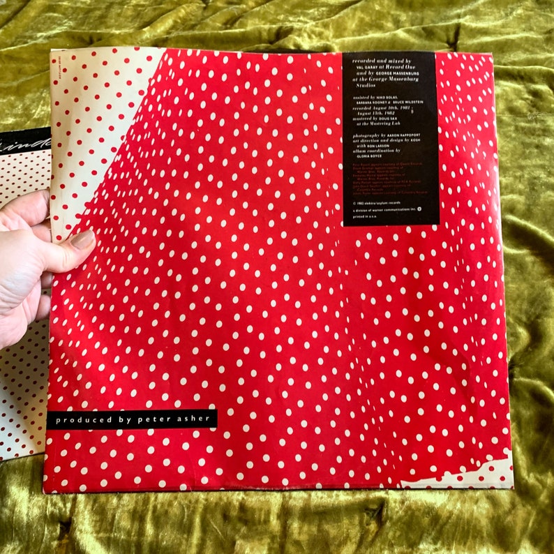 May include: Red vinyl record with white polka dots. The back cover features text that reads "produced by peter asher" and credits for the recording and production of the album.