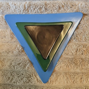 May include: A set of three nested triangular ceramic plates. The largest plate is light blue, the middle plate is forest green, and the smallest center plate is dark brown. Each plate features smooth, glossy surfaces and rounded corners.