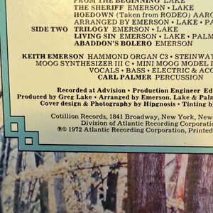 May include: Close-up of a vintage vinyl record album cover. The album's tracklist is displayed in bold, black text against a cream-colored background. The album title and artist are not visible. The cover features a nature scene with trees and foliage.