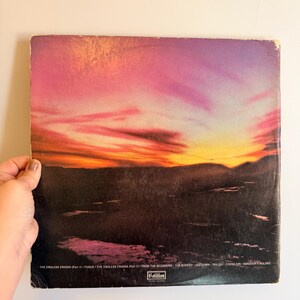May include: Vintage vinyl record album cover featuring a sunset landscape with vibrant pink, orange, and purple hues. The album cover has the text "THE ENDLESS ENIGMA" and other song titles. The Cotillion label is visible.