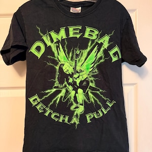 May include: A black short-sleeve t-shirt featuring a bright green graphic of a person playing an electric guitar with lightning bolts in the background. The text "DIMEBAG" is printed above the graphic, and "GETCHA PULL" is printed below it.