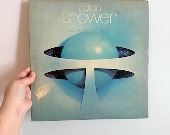 May include: Vintage vinyl record album cover for Robin Trower's "Twice Removed From Yesterday." The album art features a blue and white abstract design with the artist's name and album title in white text. The cover has a light blue background.
