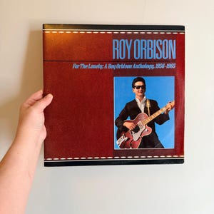 May include: A white ceramic mug with a black handle and the text "But First, Coffee" in a handwritten style. The mug is on a white surface. The mug is approximately 4 inches tall.