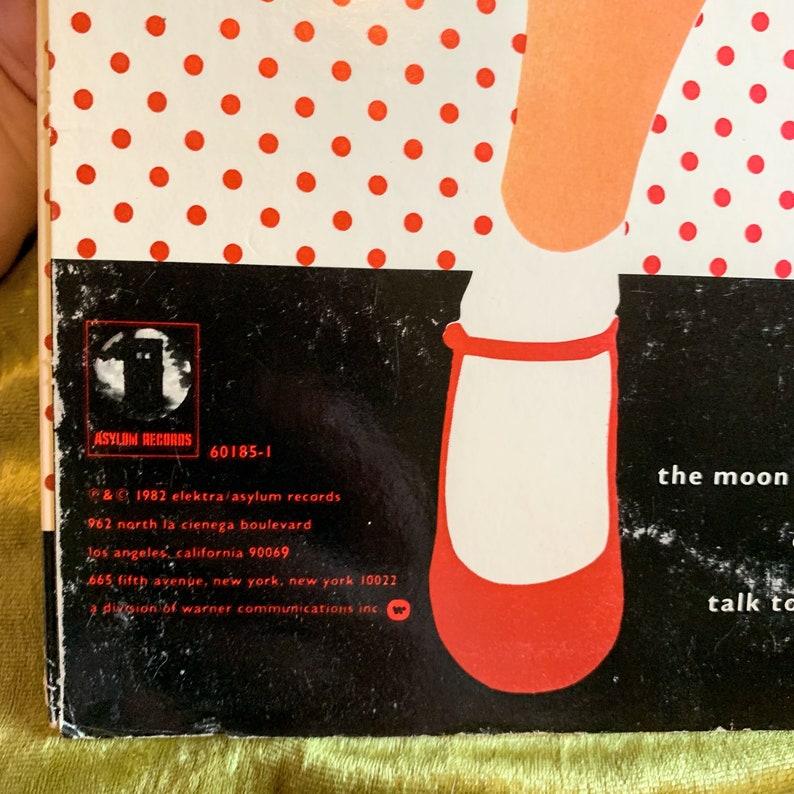 May include: Black and white record album cover with red polka dots. The album cover features a red shoe and the text "the moon talk to". The album is by Asylum Records and is titled "60185-1".