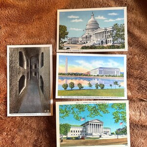 May include: A collection of vintage postcards featuring architectural landmarks in Washington, D.C. The postcards depict the U.S. Capitol, the Supreme Court Building, the Washington Monument, and the Franciscan Monastery.