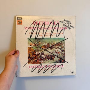 May include: A vintage vinyl record album cover featuring the text "Beethoven Symphony No. 2 in Major" and a winter scene illustration. The cover is crossed out with black marker and has the handwritten text "Another Monty Python Record".