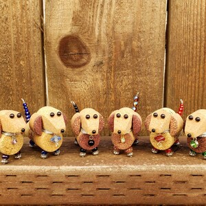 May include: Six miniature dachshund figurines made from wine corks, each with a different colored beaded tail and decorative accents.