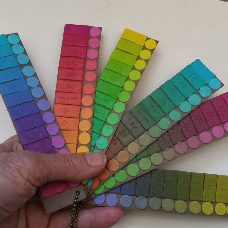 May include: A rainbow color chart with numbered swatches of paint. The chart is made of cardboard and has a metal ring attached to it.