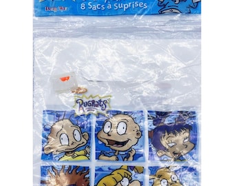 May include: A package of 8 clear plastic party favor bags featuring the Rugrats characters. The bags are decorated with images of Tommy Pickles, Chuckie Finster, Phil and Lil DeVille, Angelica Pickles, and Susie Carmichael. The package says "8 Party Gift Bags" and "8 Sacs à surprises".