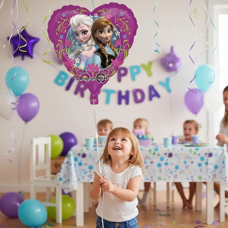 Puede incluir: Un globo morado en forma de coraz&oacute;n con Elsa y Anna de Frozen, con el texto "Happy Birthday" en el fondo. La escena incluye a una ni&ntilde;a peque&ntilde;a sosteniendo el globo, rodeada de otros globos y decoraciones de fiesta.