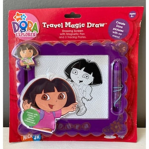 May include: A Dora the Explorer Travel Magic Draw drawing screen with a magnetic pen and tracing plates. The packaging is red and purple, featuring Dora illustrations and text. The product is for ages 4+.