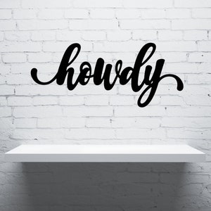 May include: A white shelf with the word "howdy" written in black cursive script on a white brick wall background.