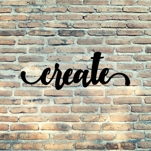 May include: The word "create" written in black cursive lettering on a brick wall background.