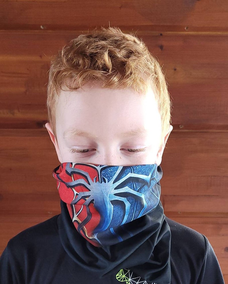 May include: A young person wearing a black shirt with a red and blue patterned neck gaiter. The gaiter features a spider web design.