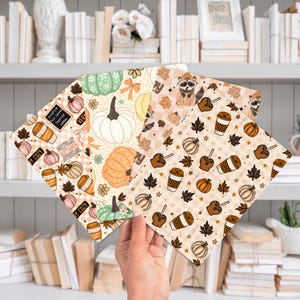 May include: Four sheets of patterned paper with autumn themes. Designs include pumpkins, coffee cups, maple leaves, and a raccoon. Colors are beige, orange, brown, and green. One sheet has text that reads "Autumn, Pumpkin, Fall Leaves, Latte, Cozy".