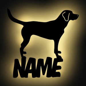 May include: Black silhouette of a dog with the word "NAME" underneath. The dog is standing on a light yellow background.