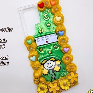Puede incluir: Funda de teléfono verde con un diseño de personaje pixelado, adornada con flores amarillas, corazones y elementos decorativos. La funda presenta el texto "Despite everything, it's still you." y está tematizada en el videojuego Undertale.