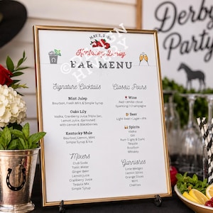 May include: A framed bar menu with a gold border, featuring a "Kentucky Derby" theme. The menu lists signature cocktails, classic pours, mixers, and garnishes. Red roses and white hydrangeas are in silver vases.