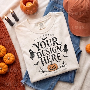 May include: A cream-colored t-shirt featuring a black graphic with the text "ATLAS MOCKUPS YOUR DESIGN HERE PREMIUM SPOOKY MOCKUPS" surrounded by illustrations of two ghosts, three bats, a jack-o'-lantern, and bare tree branches.