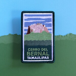 Könnte beinhalten: Ein grüner gestickter Patch mit weißem Rand. Der Patch zeigt einen rosa und braunen Berg mit grünem Sockel und blauem Himmel mit weißen Wolken. Der Text "CERRO DEL BERNAL TAMAULIPAS" ist in Grün auf dem Patch aufgedruckt.