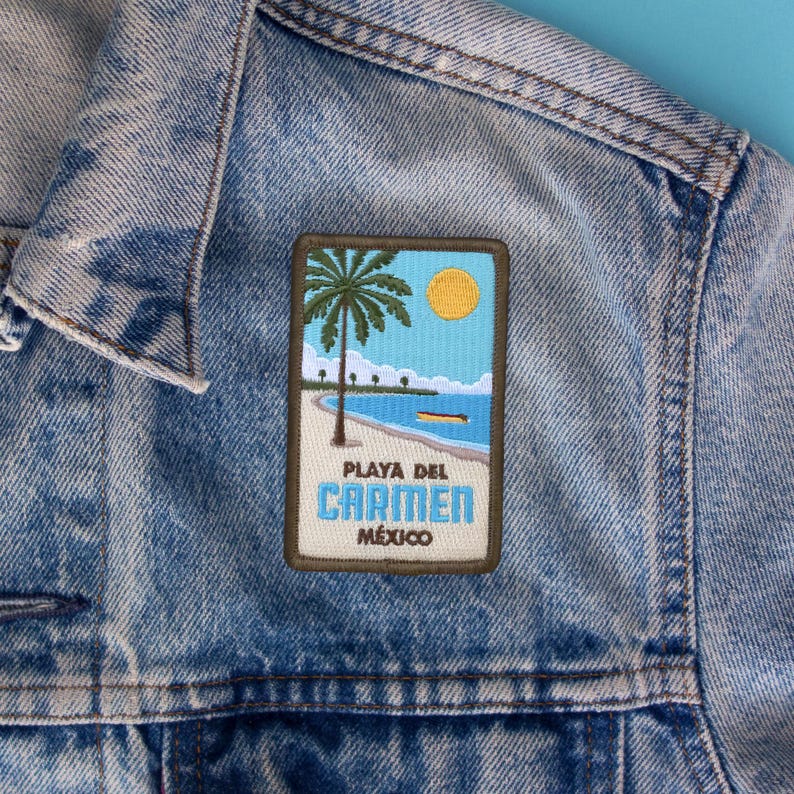 May include: A blue denim jacket with a brown and green embroidered patch that says "Playa del Carmen, Mexico" with a palm tree and a beach scene.