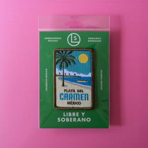 May include: A green and brown embroidered patch with a beach scene. The patch features a palm tree, a blue ocean, and a yellow sun. The text "Playa del Carmen, Mexico" is embroidered on the patch.