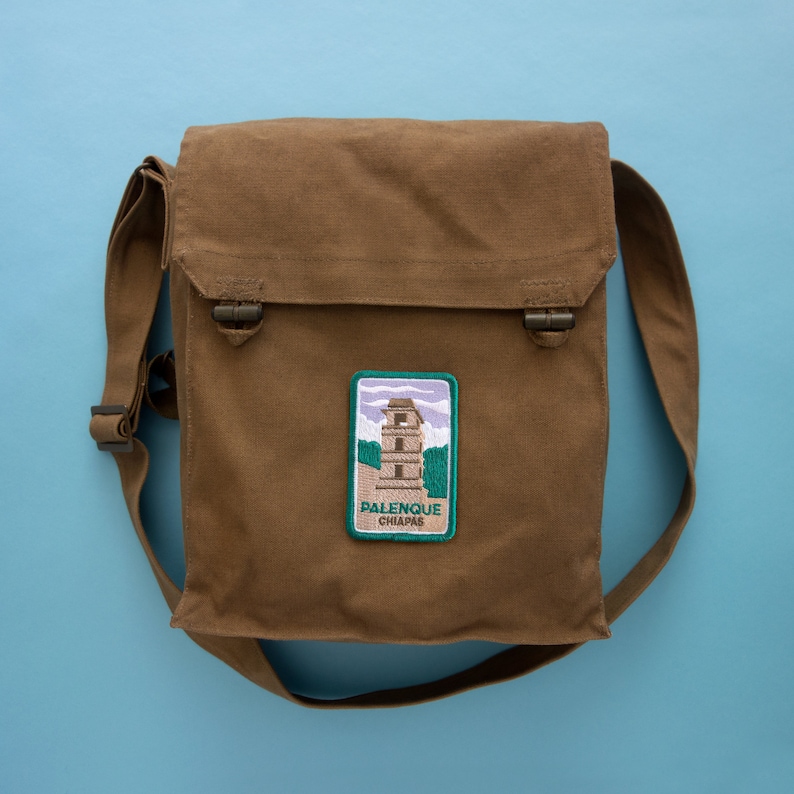 May include: A brown canvas messenger bag with a green and white embroidered patch that says "Palenque Chiapas".