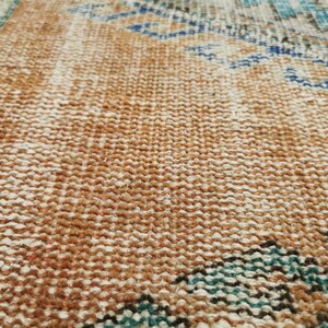 May include: Close-up of a woven rug with a brown, white and blue pattern. The rug has a textured surface and a fringe border.