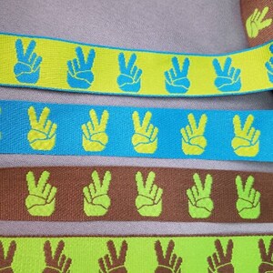 Met de hand jacquardgeweven lint met vredesteken, 1 inch breed, op maat gesneden.