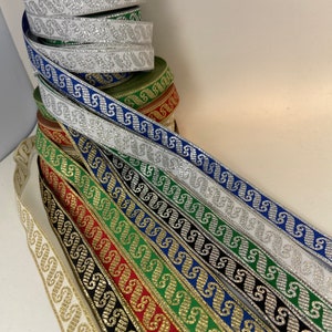 May include: A collection of decorative ribbons in various colors, including gold, silver, blue, green, and red. Each ribbon features a repeating silver and gold pattern. The ribbons are stacked and fanned out, showcasing their design.