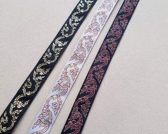 May include: Three decorative ribbons with ornate floral patterns. One ribbon is black with gold accents, another is white with copper accents, and the third is black with red accents. The ribbons are likely used for crafting or embellishment.