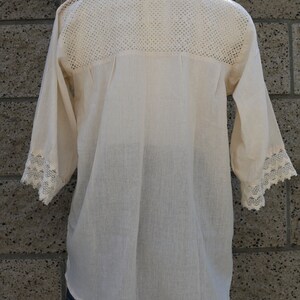 May include: A white crochet top with a lace trim on the sleeves and neckline. The top is made of a lightweight fabric and has a relaxed fit.