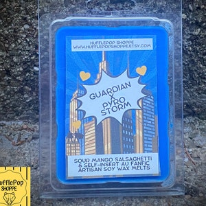 Può includere: Un contenitore di cera da sciogliere blu con un'immagine in stile fumetto di uno skyline urbano e il testo "GUARDIAN x PYRO STORM". Il testo "SOUR MANGO SALSAGHETTI & SELF-INSERT AU FANFIC ARTISAN SOY WAX MELTS" è stampato sotto l'immagine.