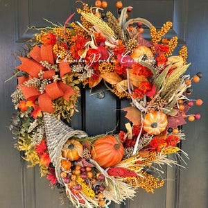 May include: A fall-themed wreath with a cornucopia design. The wreath features orange pumpkins, berries, and leaves, with a large orange bow. The text "Chunka Pookie Creations" is visible on the wreath.