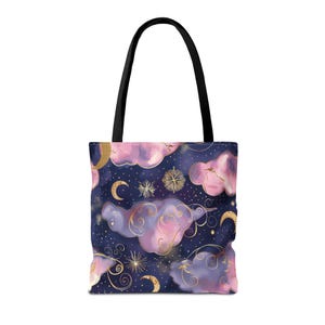 Puede incluir: Bolso tote con un diseño celestial. El bolso presenta un fondo azul oscuro con nubes rosas y moradas, estrellas doradas, lunas y espirales decorativas. El bolso tiene asas negras.
