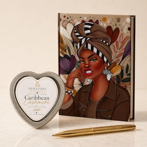 May include: A heart-shaped metal candle tin labeled Herstory Scribbles Caribbean Cashmere, a hardcover journal featuring an illustration of a person in a brown headwrap and jacket, and a gold-toned ballpoint pen with the word Herstory printed on it.